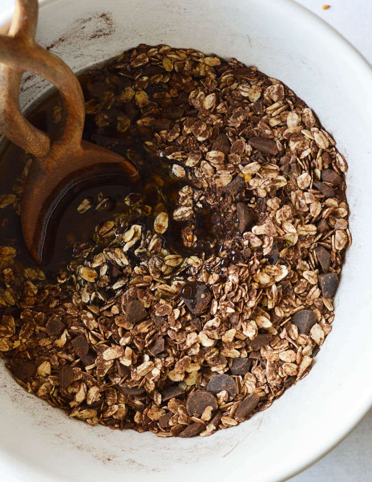 oats mixed with cocoa powder in a bowl with maple syrup and coconut oil on top.