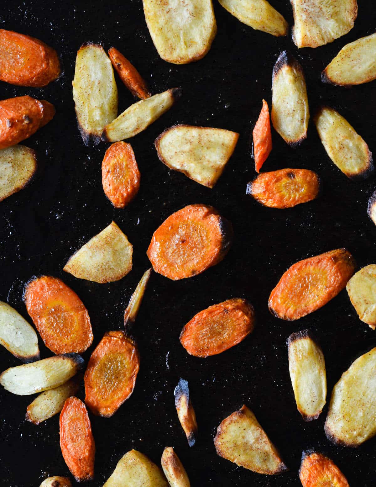 close up of roasted carrots and parsnips on a sheet pan.