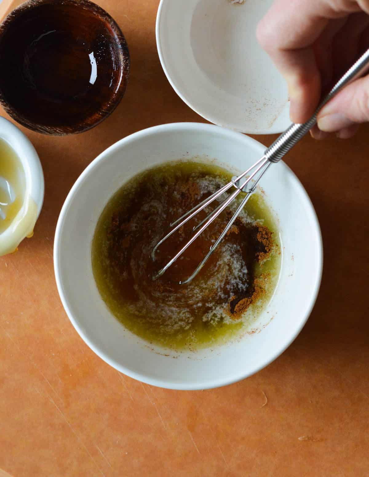 a small bowl of melted butter, cinnamon, honey, and olive oil getting whisked together.