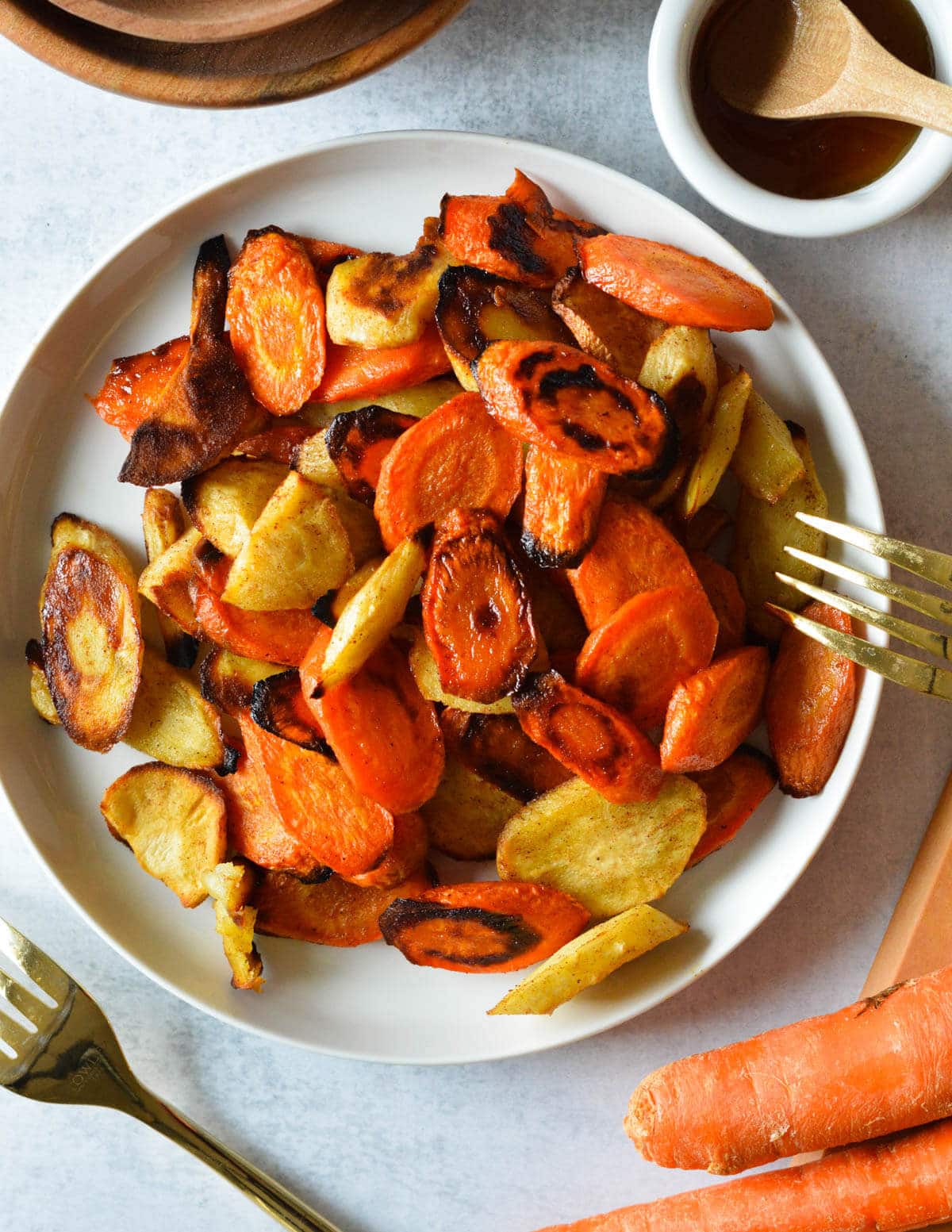 a plate of honey roasted carrots and parsnips with a gold fork next to it.