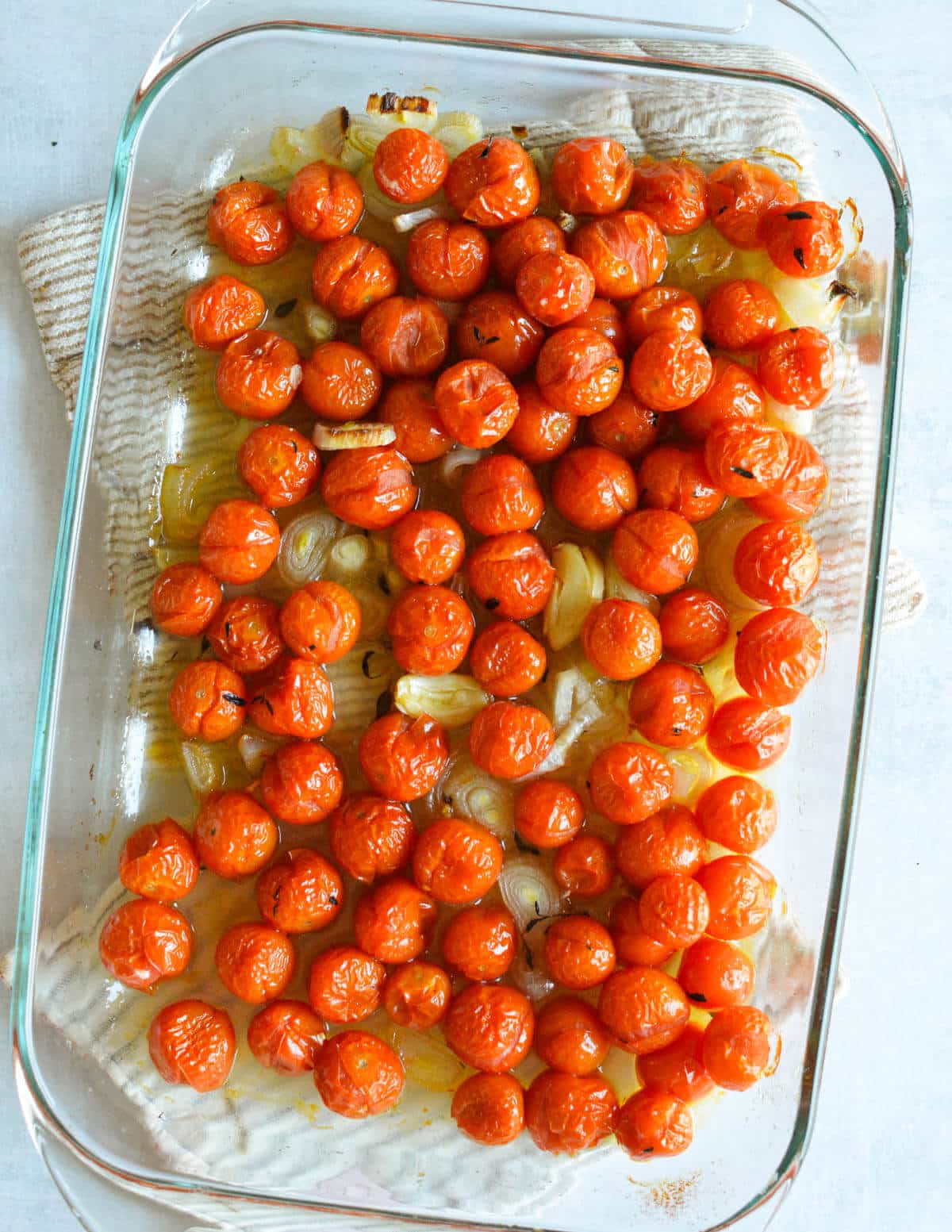 roasted cherry tomatoes, shallots, and garlic in a baking dish.