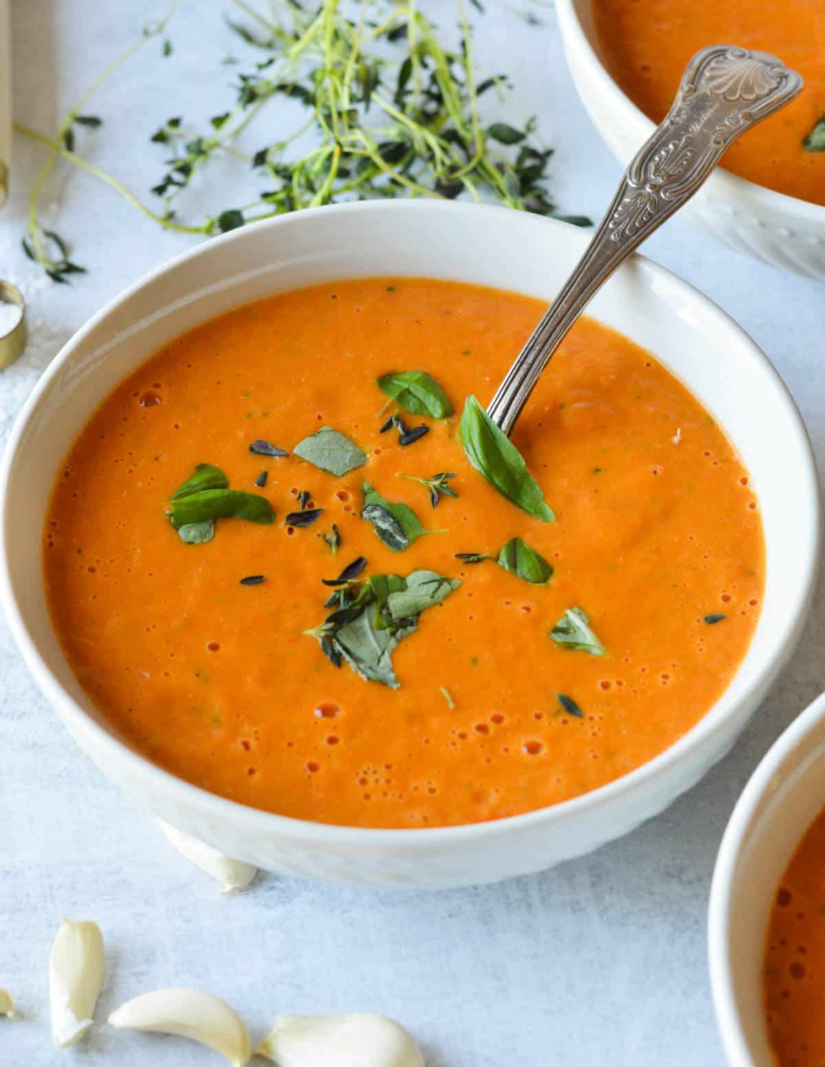 a bowl of cherry tomato soup with fresh basil on top.