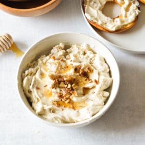 a bowl of honey walnut cream cheese with walnuts and honey on top.