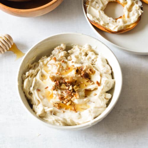 a bowl of honey walnut cream cheese with walnuts and honey on top.