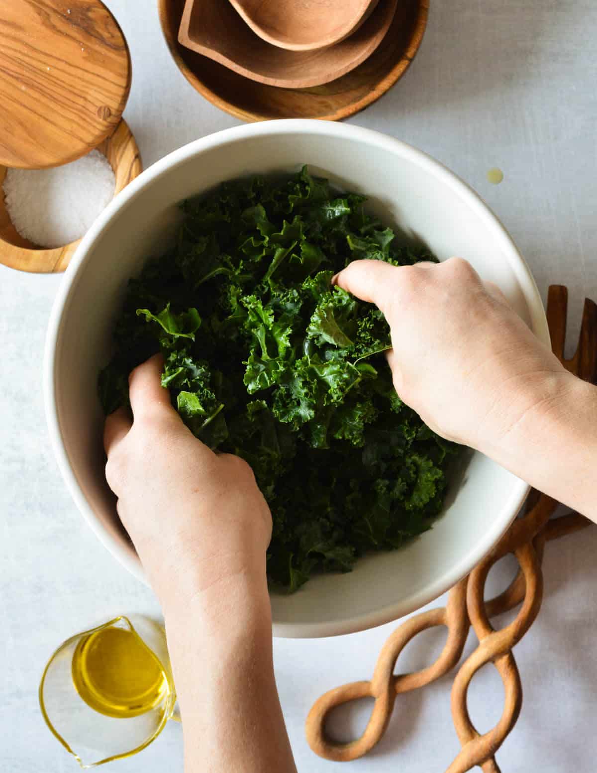 hands massaging kale leaves with oil on them.