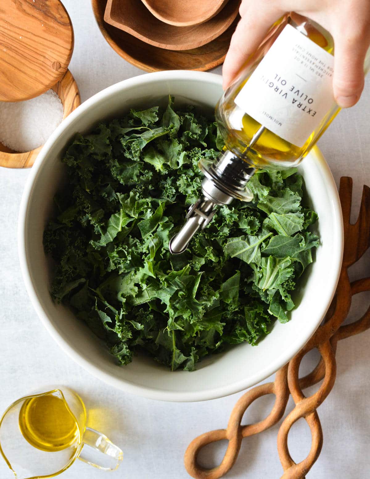drizzling olive oil onto kale leaves.