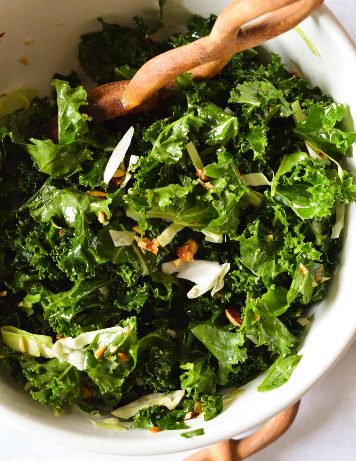 close up of a kale salad with chopped almonds and green cabbage.