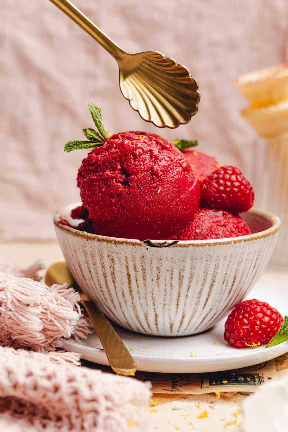 a bowl of raspberry sorbet with a golden spoon about to dig in