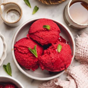 a bowl with scoops of raspberry sorbet with mint leaves on top.