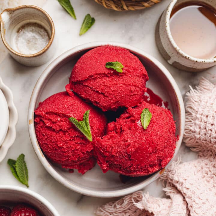a bowl with scoops of raspberry sorbet with mint leaves on top.