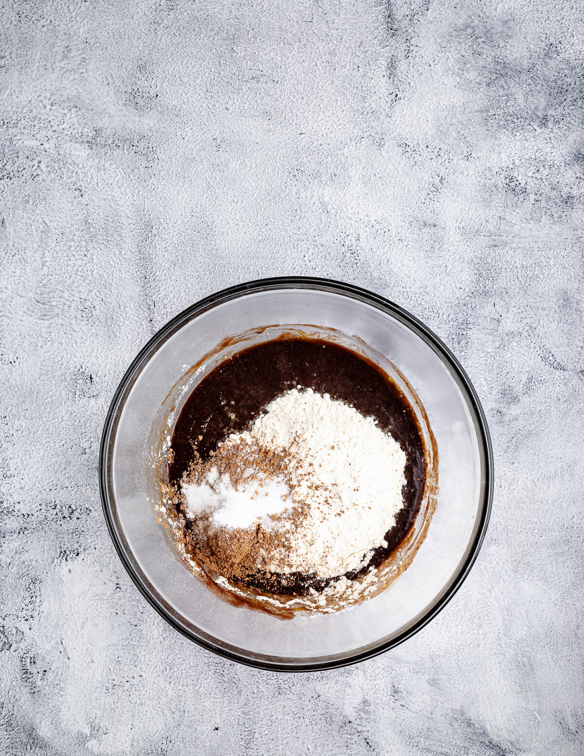 a bowl of melted chocolate with flour and cocoa powder on top.