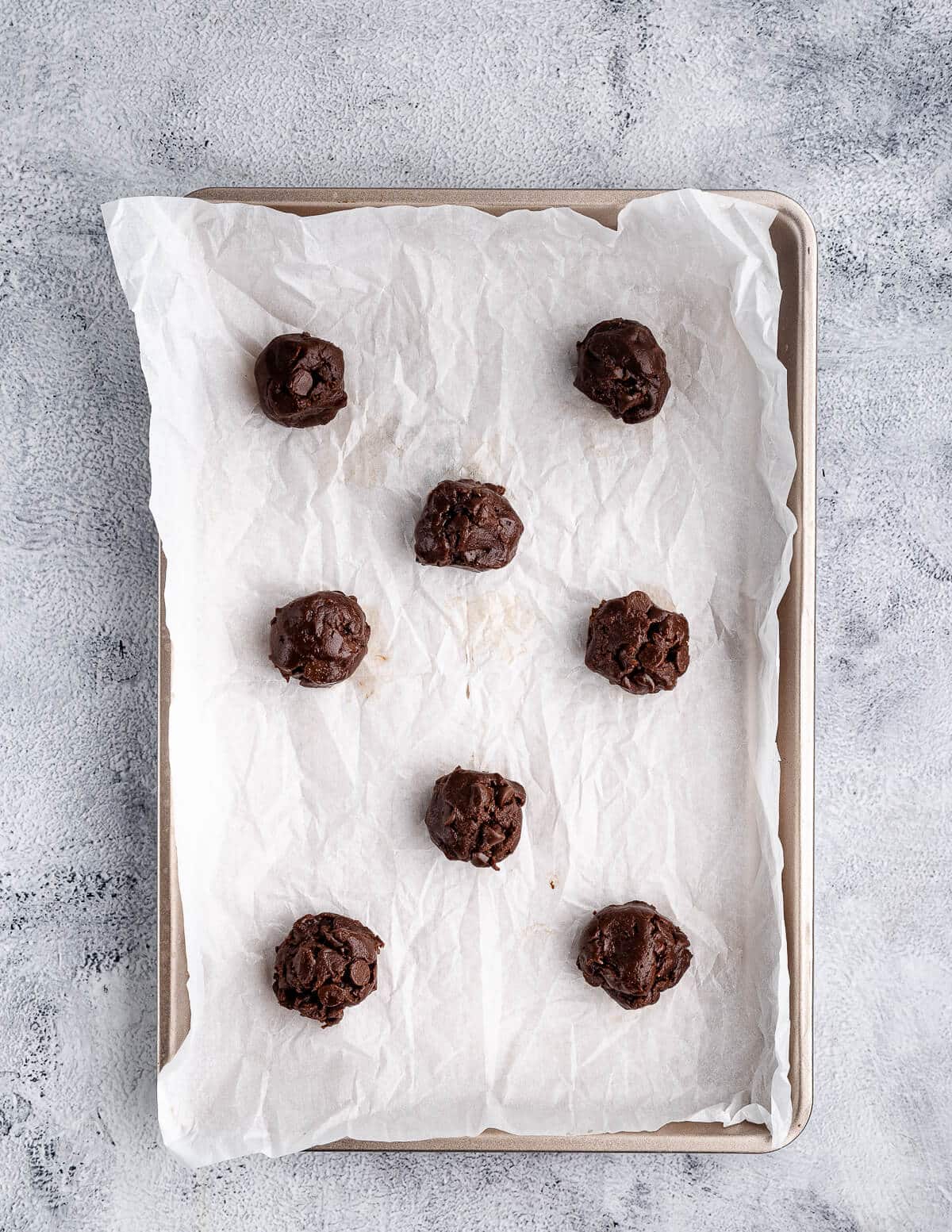 chocolate cookie dough balls on a sheet pan.