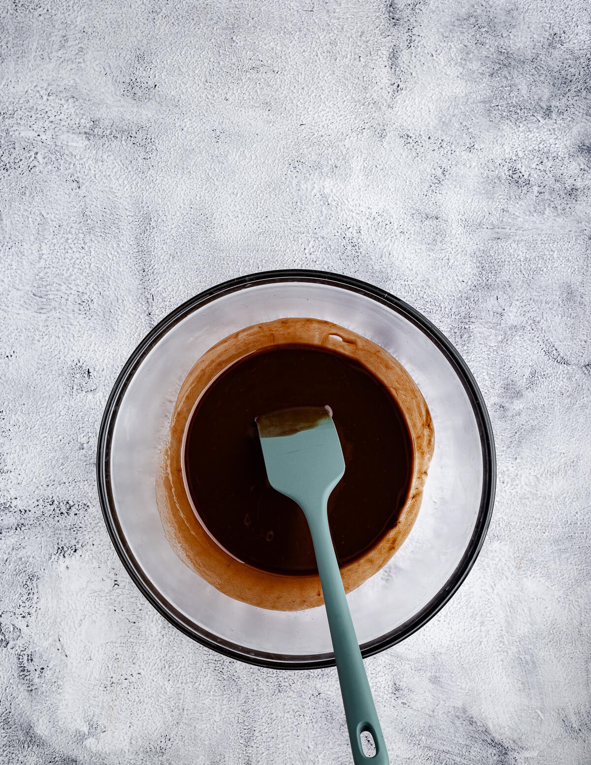 melted chocolate and butter in a bowl with a spatula.