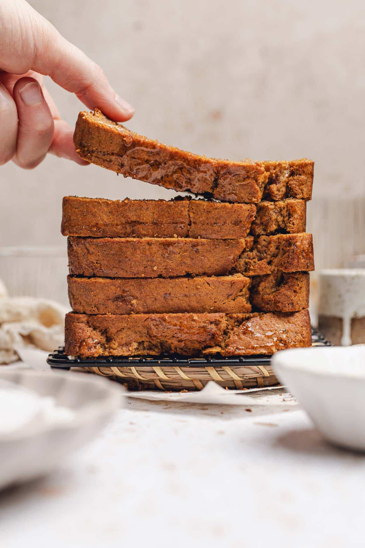 hand laying a piece of banana bread on a stack of banana bread slices.
