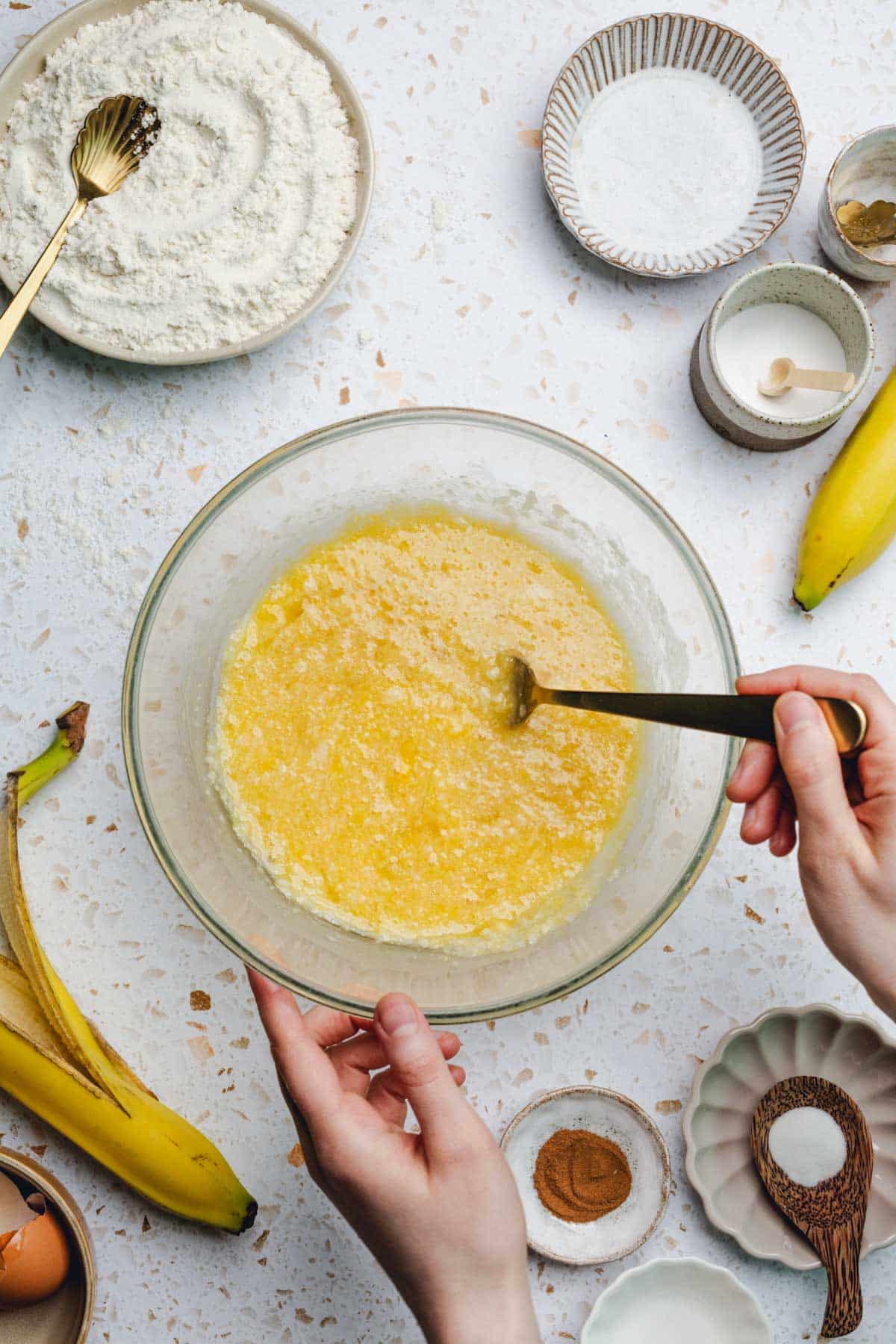 a bowl of mashed banana, oil, honey, and eggs mixed together.