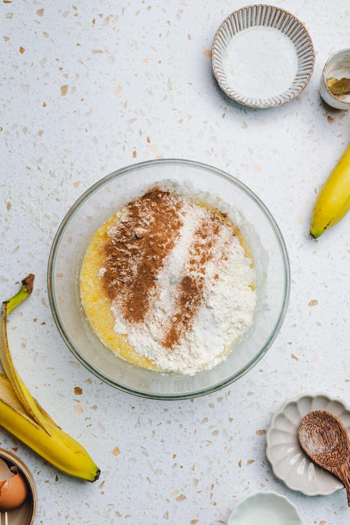 a bowl of eggs, banana, and honey with flour and cinnamon on top.
