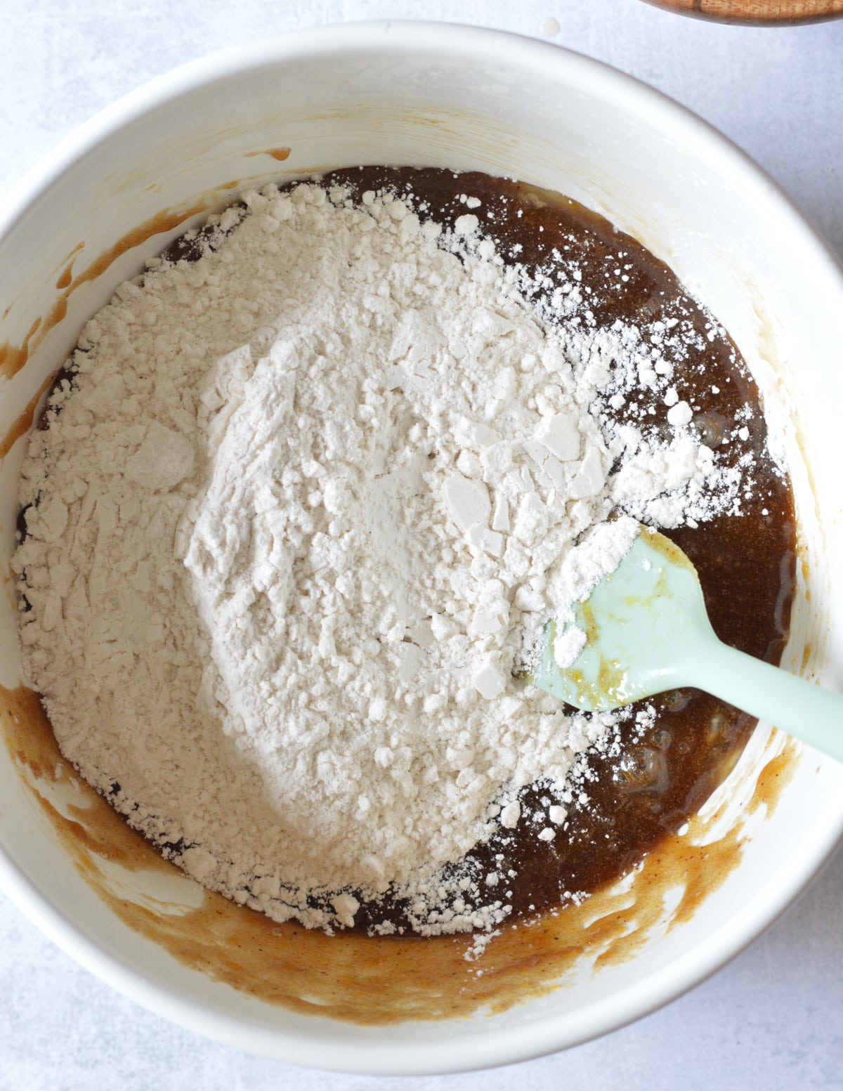 a bowl of sugar, butter, and eggs mixed together with gluten-free flour on top.