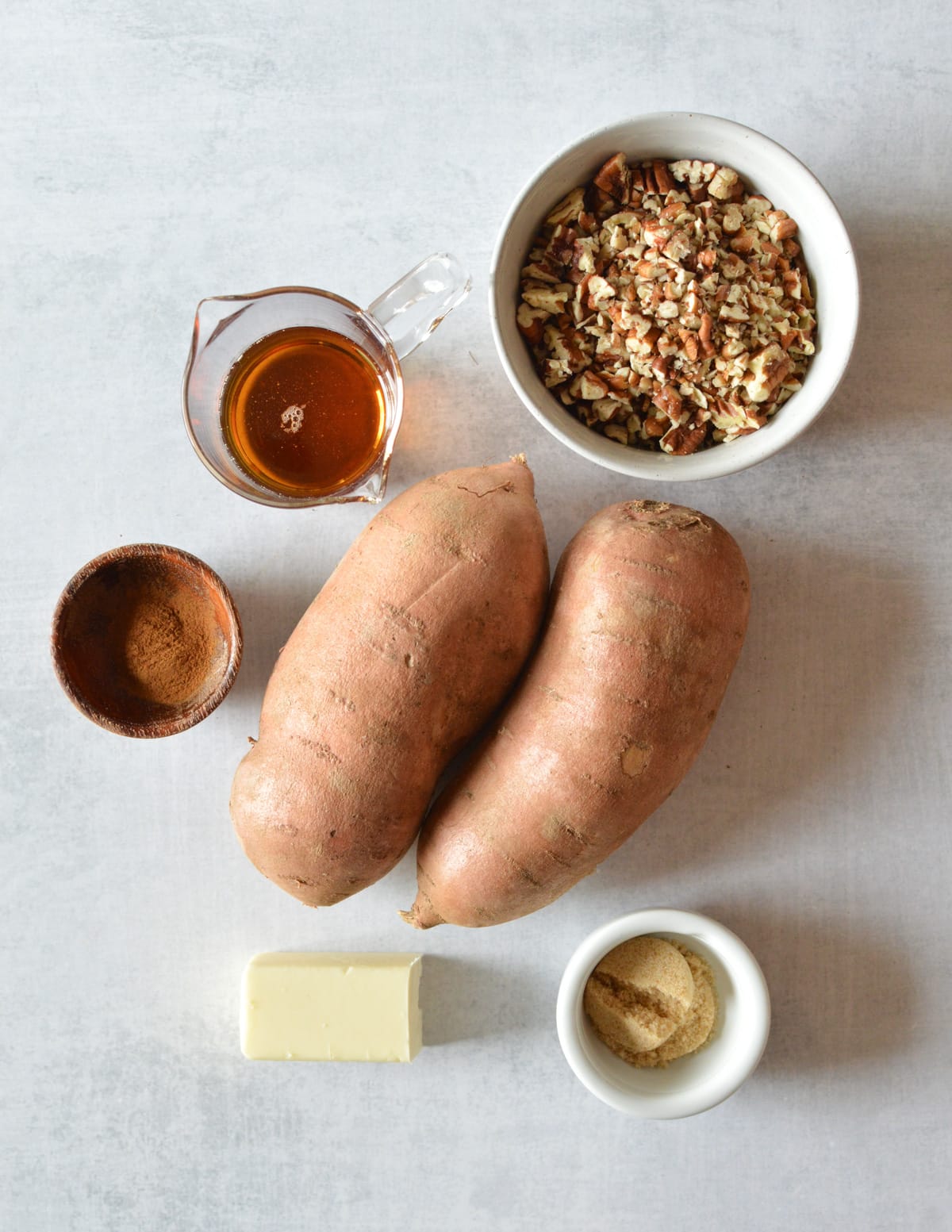 a bowl of chopped pecans, maple syrup, cinnamon,. sweet potatoes, butter, and brown sugar.