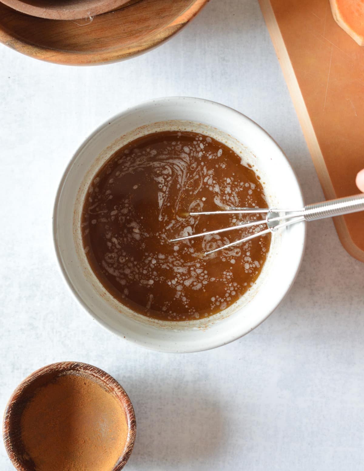 stirring a bowl of melted butter, maple syrup, and cinnamon with a mini whisk.