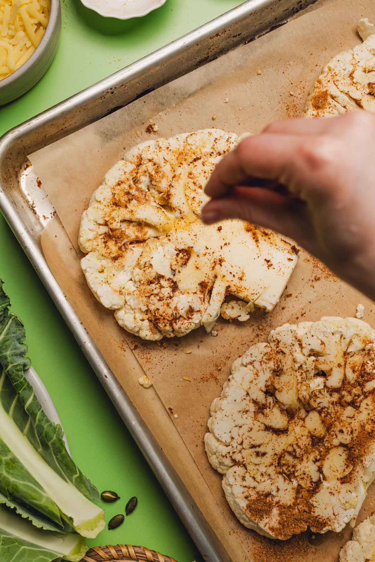sprinkling kosher salt onto seasoned cauliflower steaks.