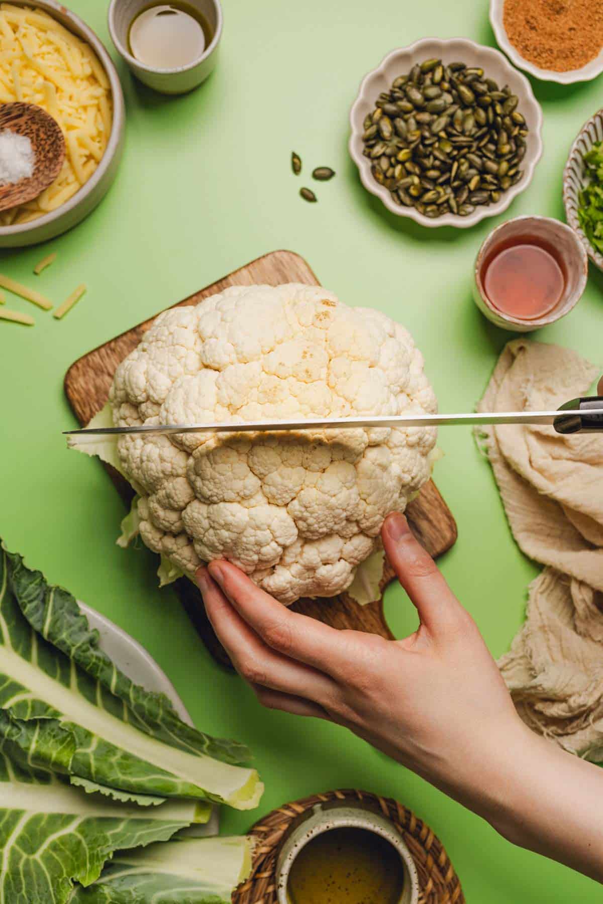 hand holding a head of cauliflower while cutting into the top of it.