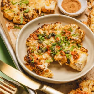 cheesy cauliflower steak with salsa and pepitas on top.
