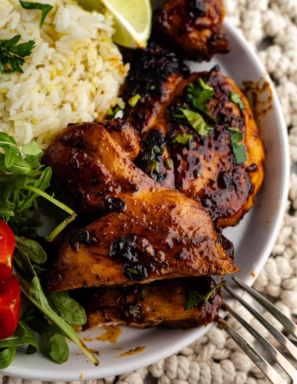 honey chipotle chicken thighs on a plate with rice and salad.