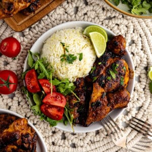 honey chipotle chicken thighs with rice and tomatoes on a plate.