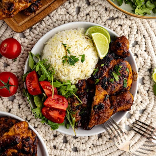 honey chipotle chicken thighs with rice and tomatoes on a plate.