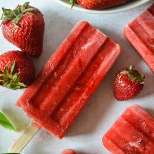 strawberry popsicle with strawberries next to it.