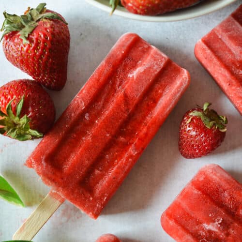 strawberry popsicle with strawberries next to it.