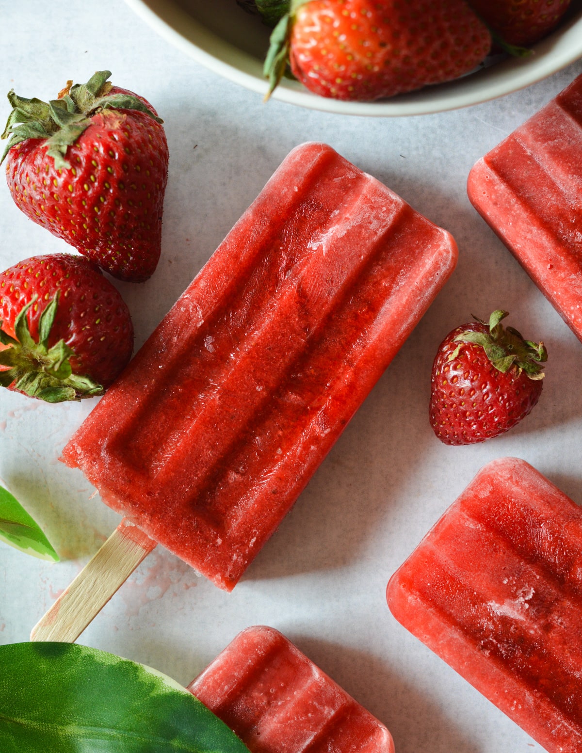 strawberry popsicles and strawberries on counter.
