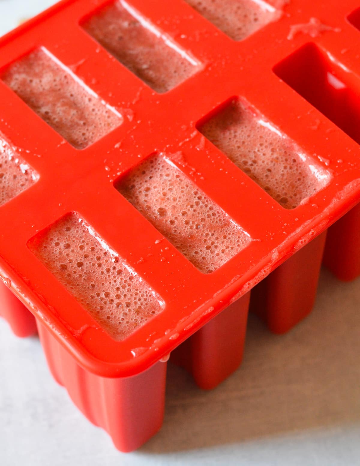 popsicle mold filled with strawberry mixture.