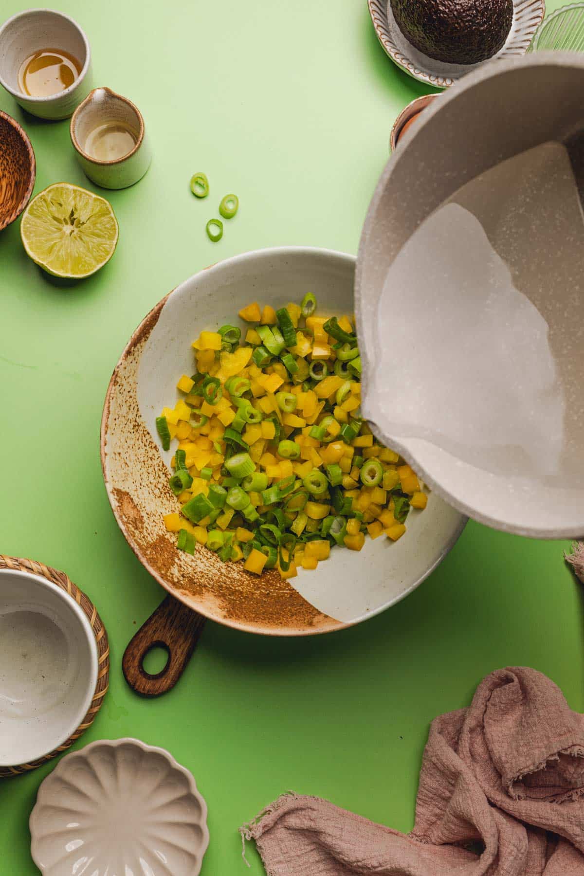 pouring hot vinegar mixture over bell peppers and green onions.