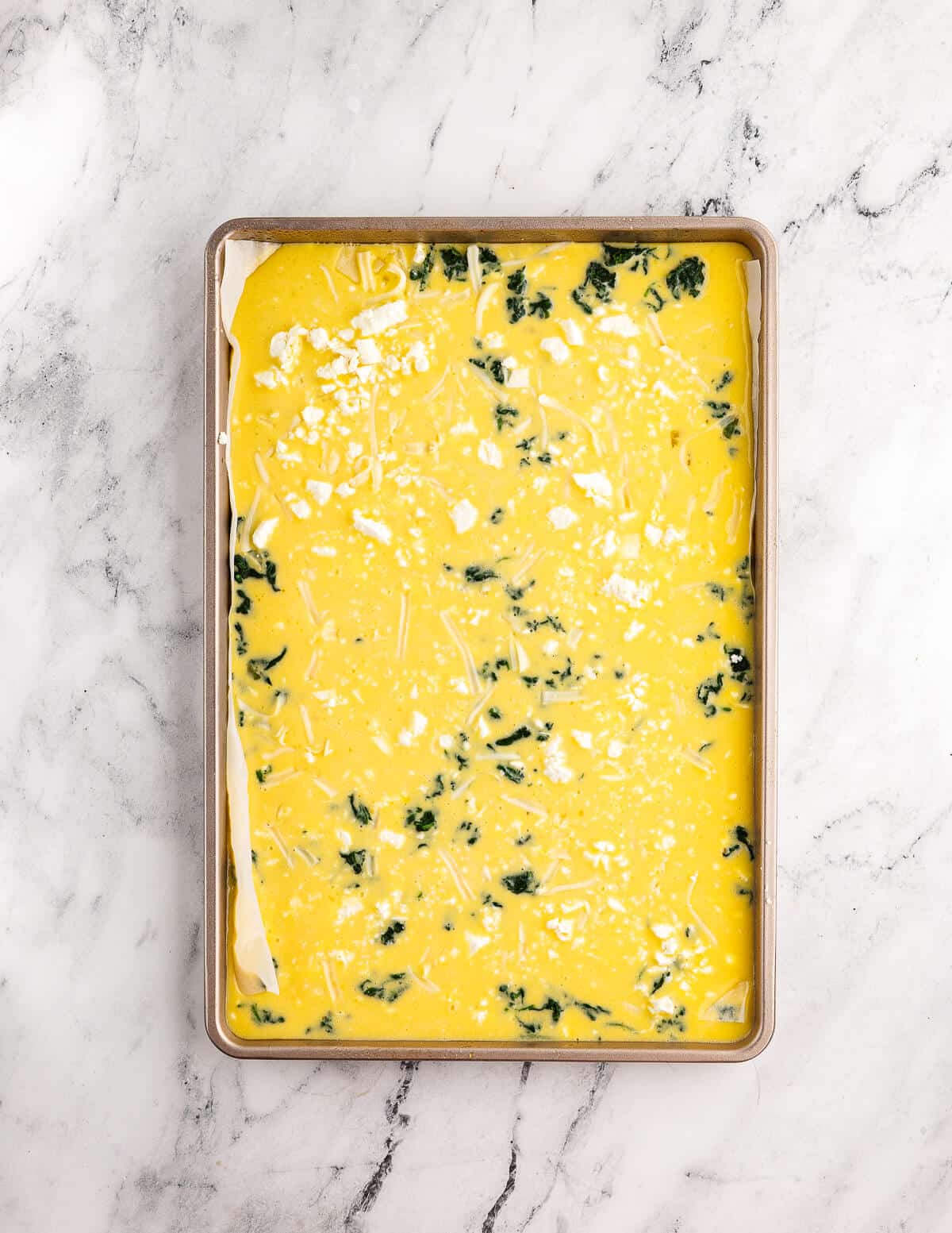 whisked eggs, spinach, and feta in a sheet pan.
