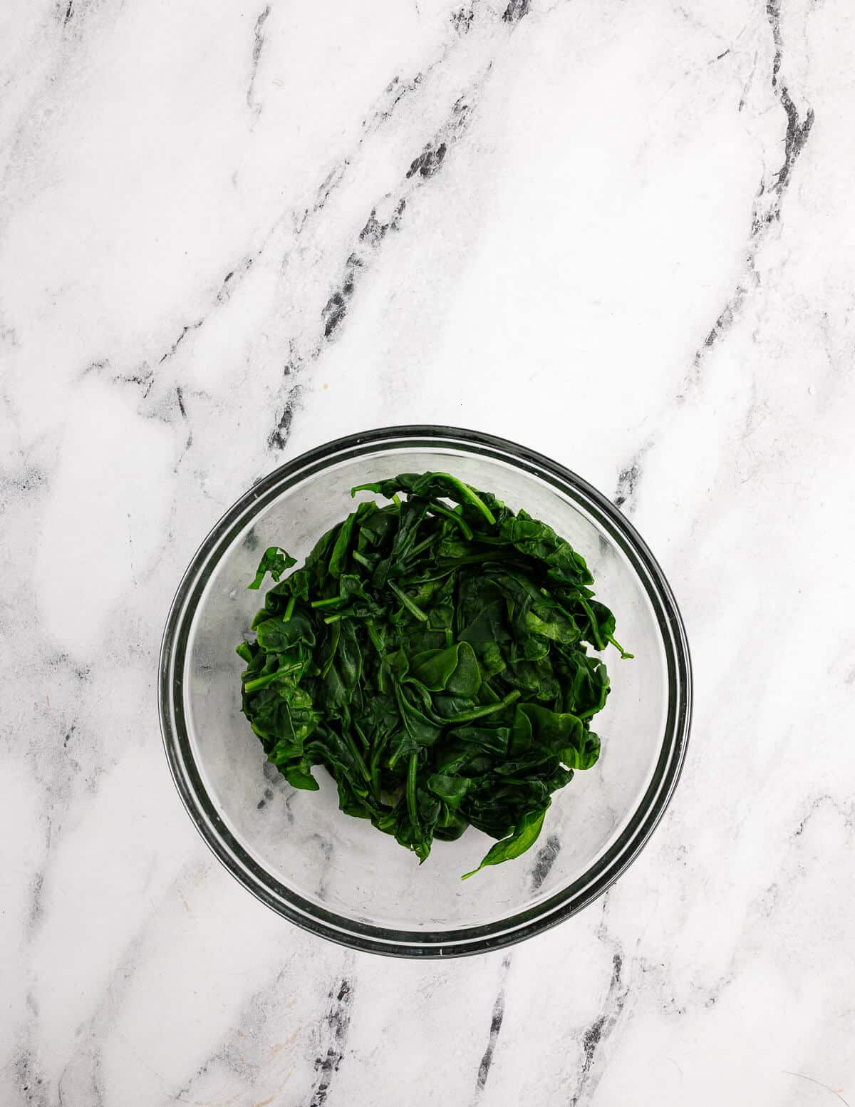 a bowl of cooked baby spinach.