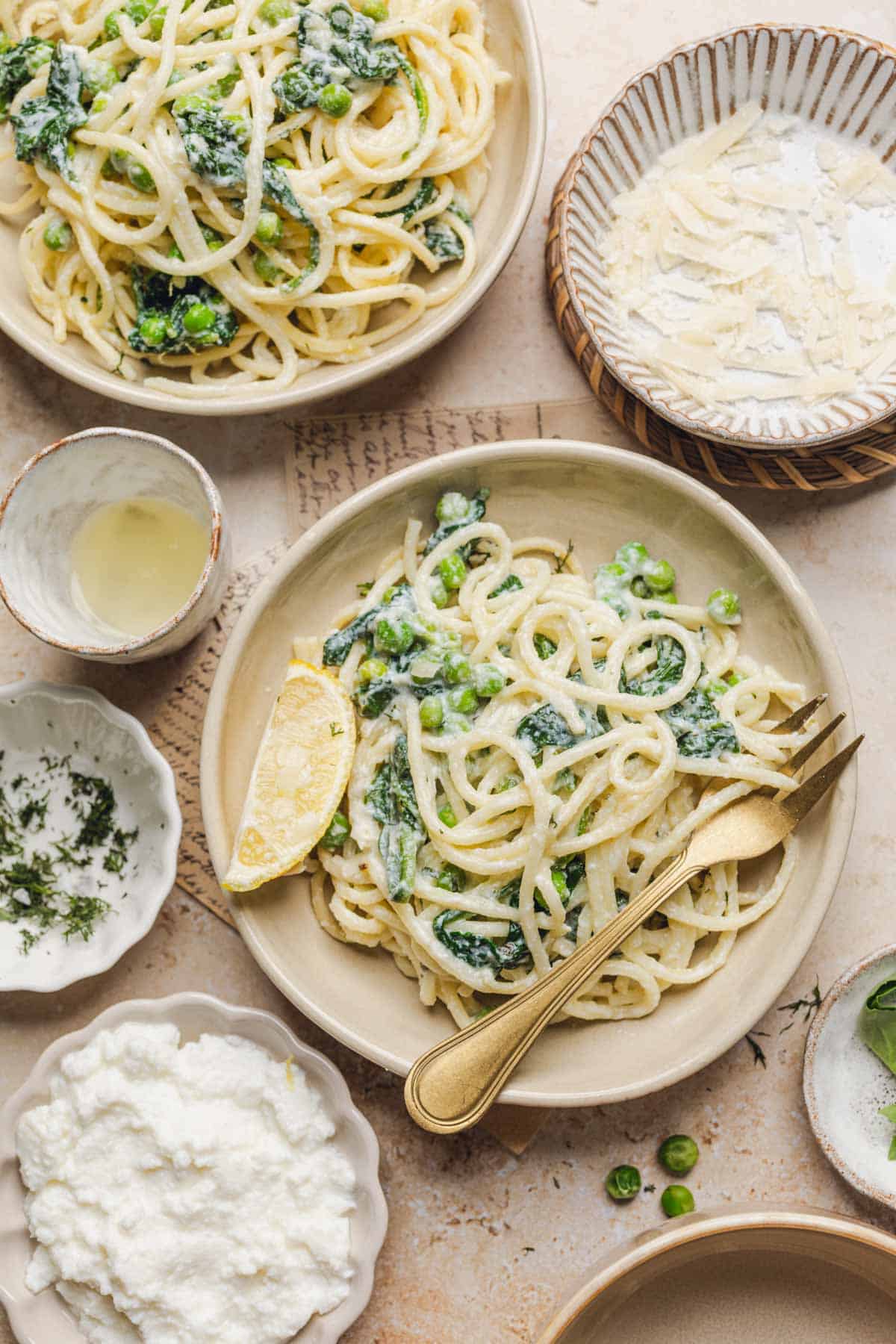 a plate of lemon ricotta pasta with a gold fork and lemon wedge.