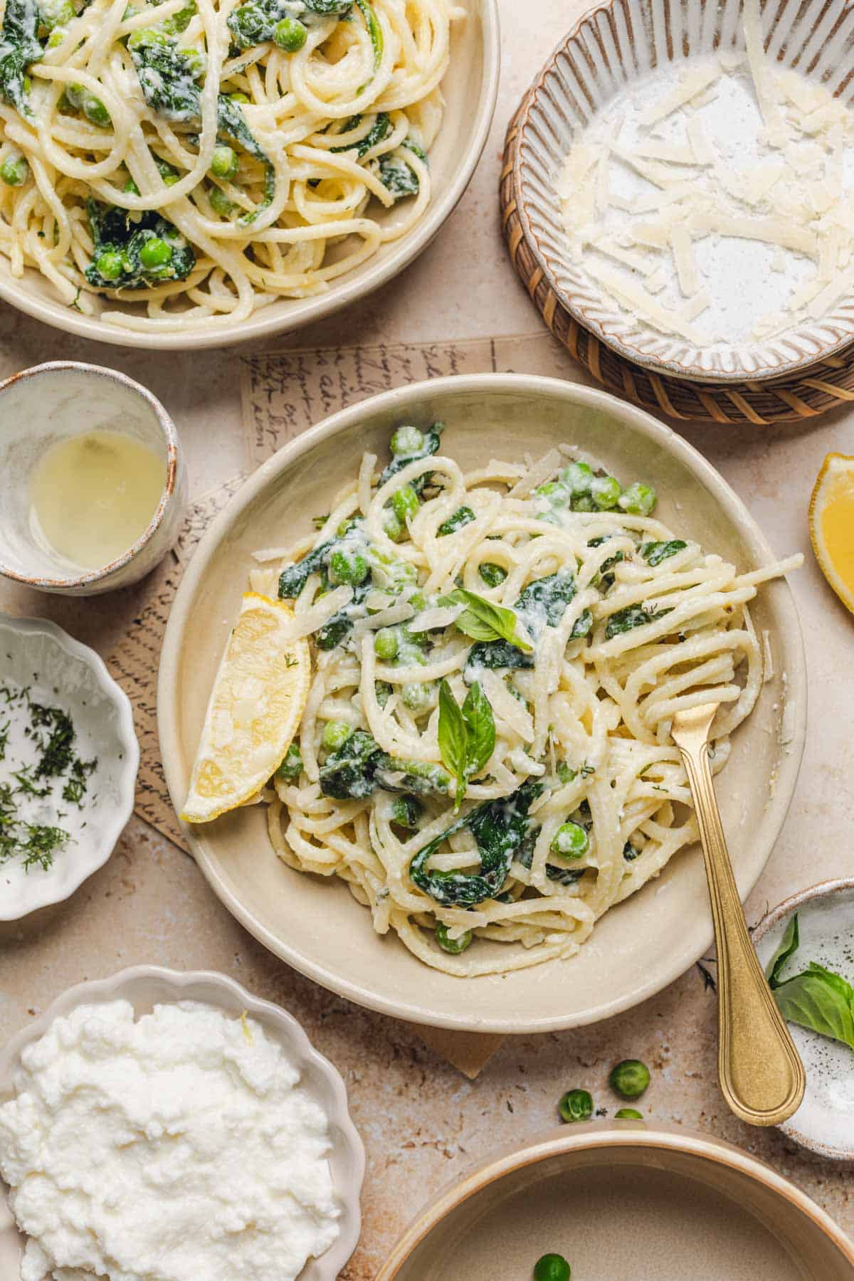 a plate with lemon ricotta pasta in it, a lemon wedge, and a fork.
