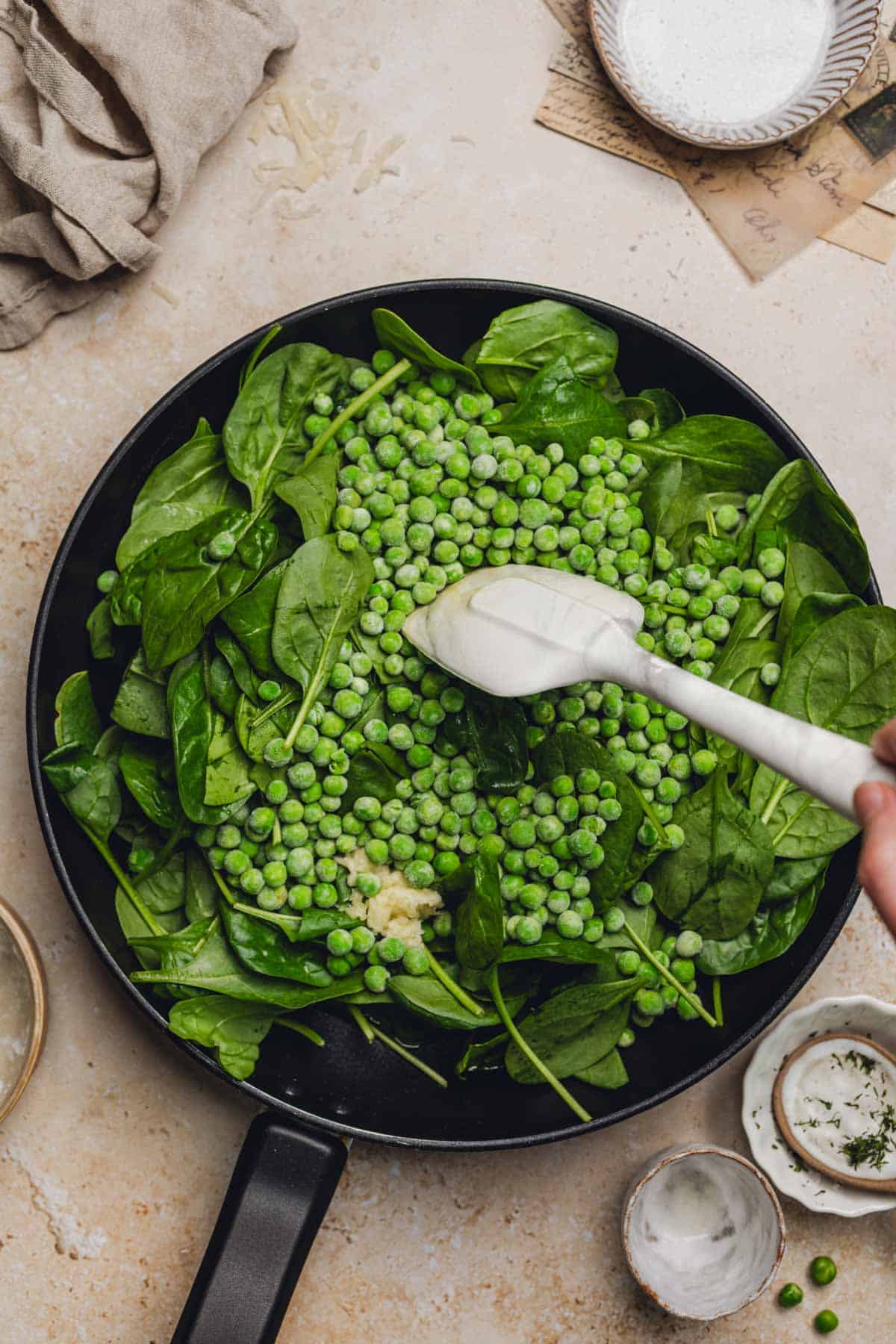 a skillet with spinach and peas.