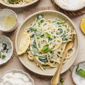 a plate with lemon ricotta pasta with a fork and lemon wedge
