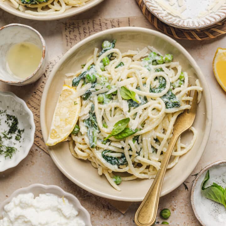 a plate with lemon ricotta pasta with a fork and lemon wedge