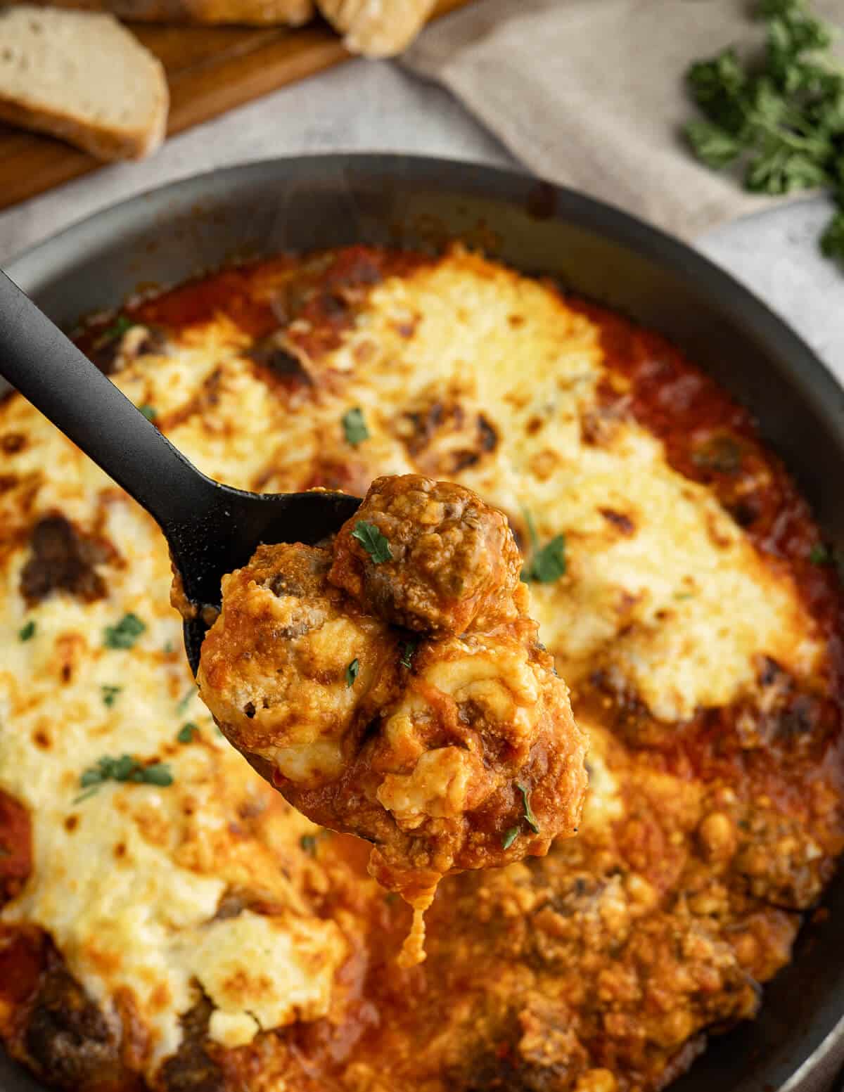 a spoonful of cheesy meatballs with marinara sauce.