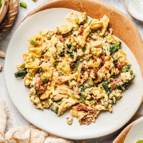 a plate of scrambled eggs with spinach and cheese