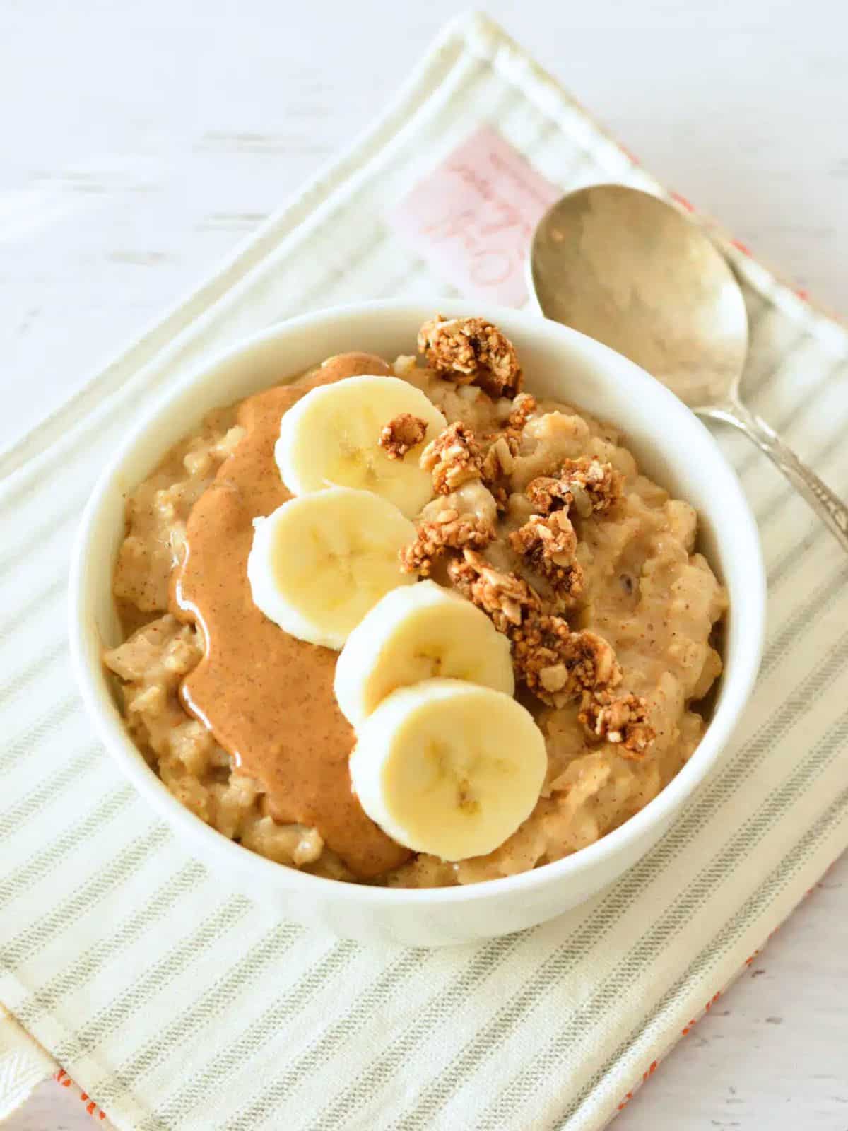 a bowl of oatmeal with peanut butter, sliced banana, and granola.