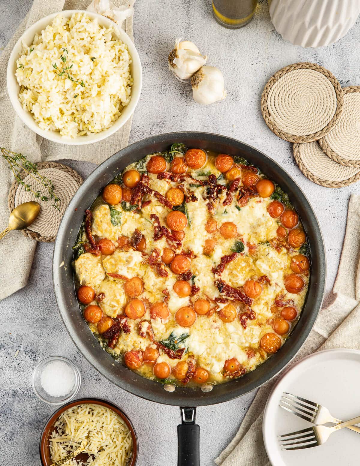 chicken meatballs in a skillet with tomatoes, sun-dried tomatoes, spinach, and ricotta cheese.