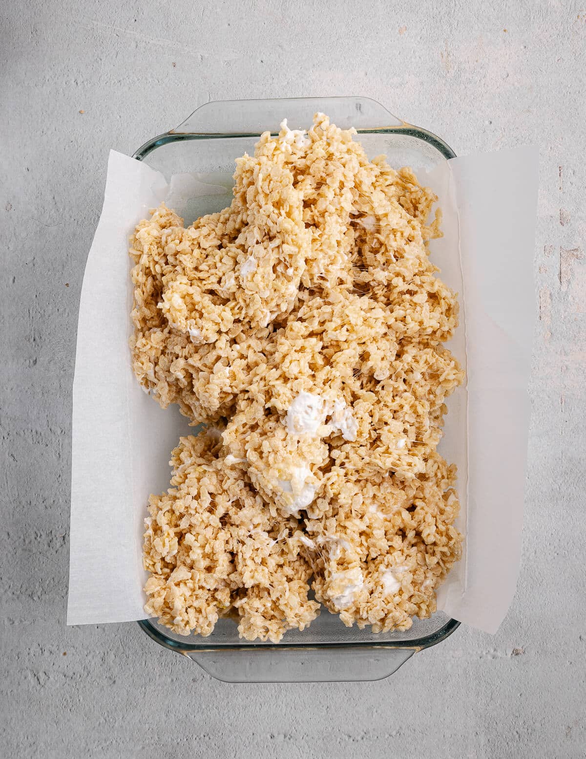 rice crispy mixture in a baking dish with parchment paper in it.