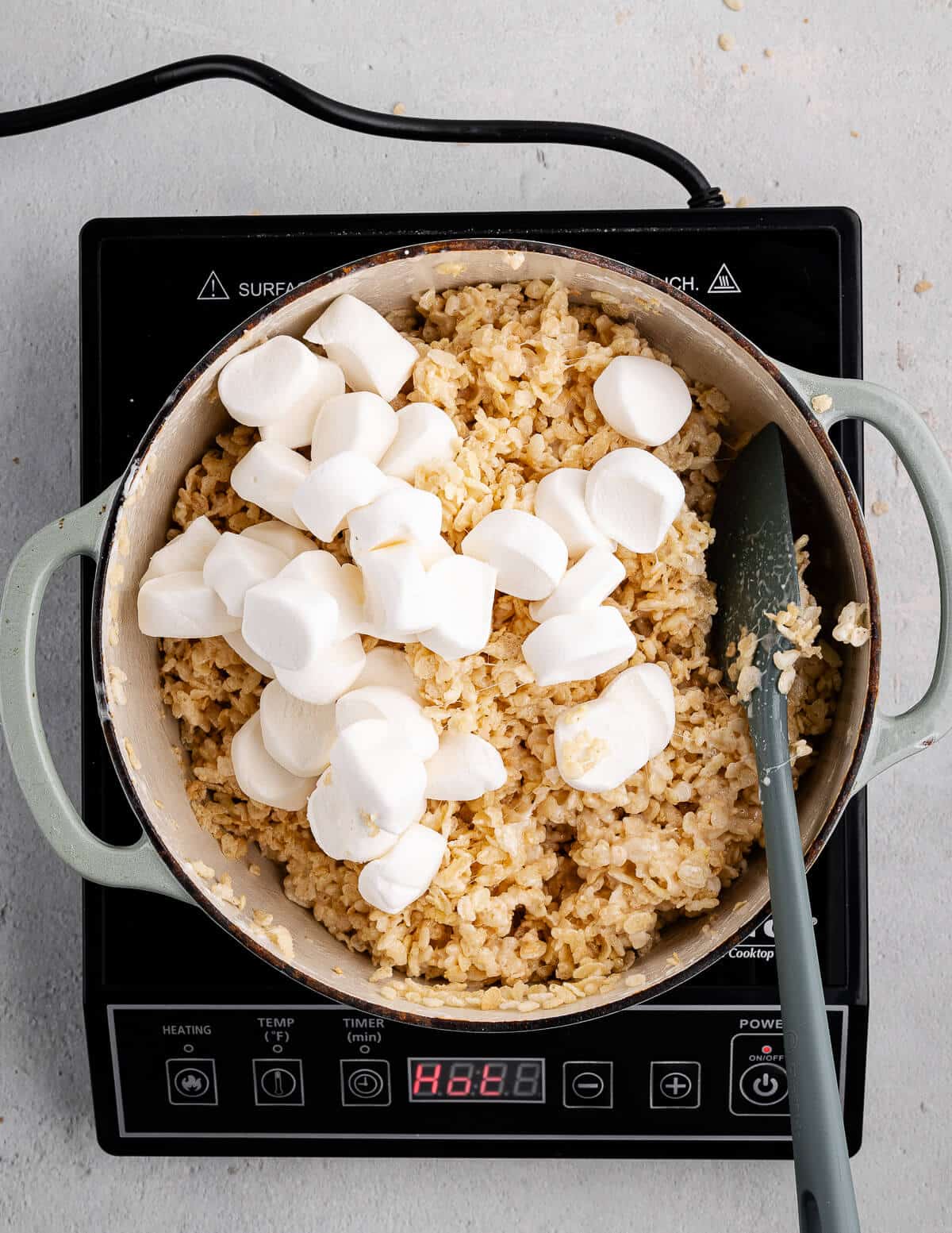 a dutch oven with sticky rice crispy mixture in it with big marshmallows on top.