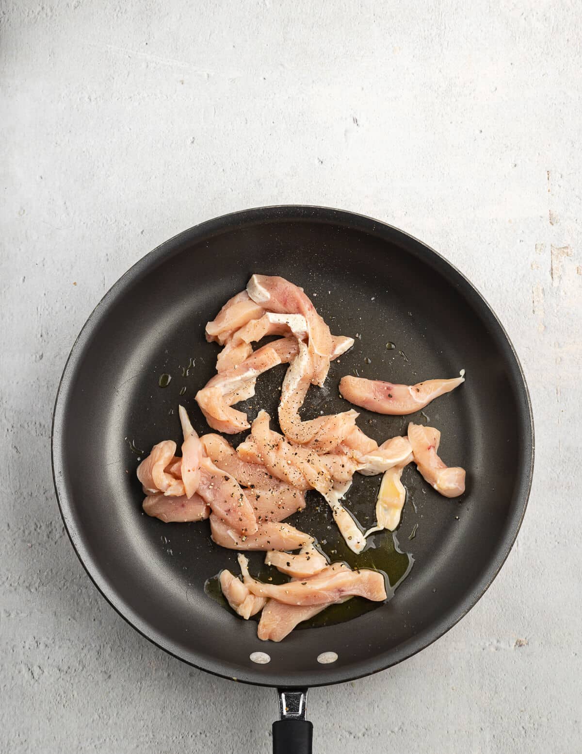 partially cooked sliced chicken in a hot skillet.