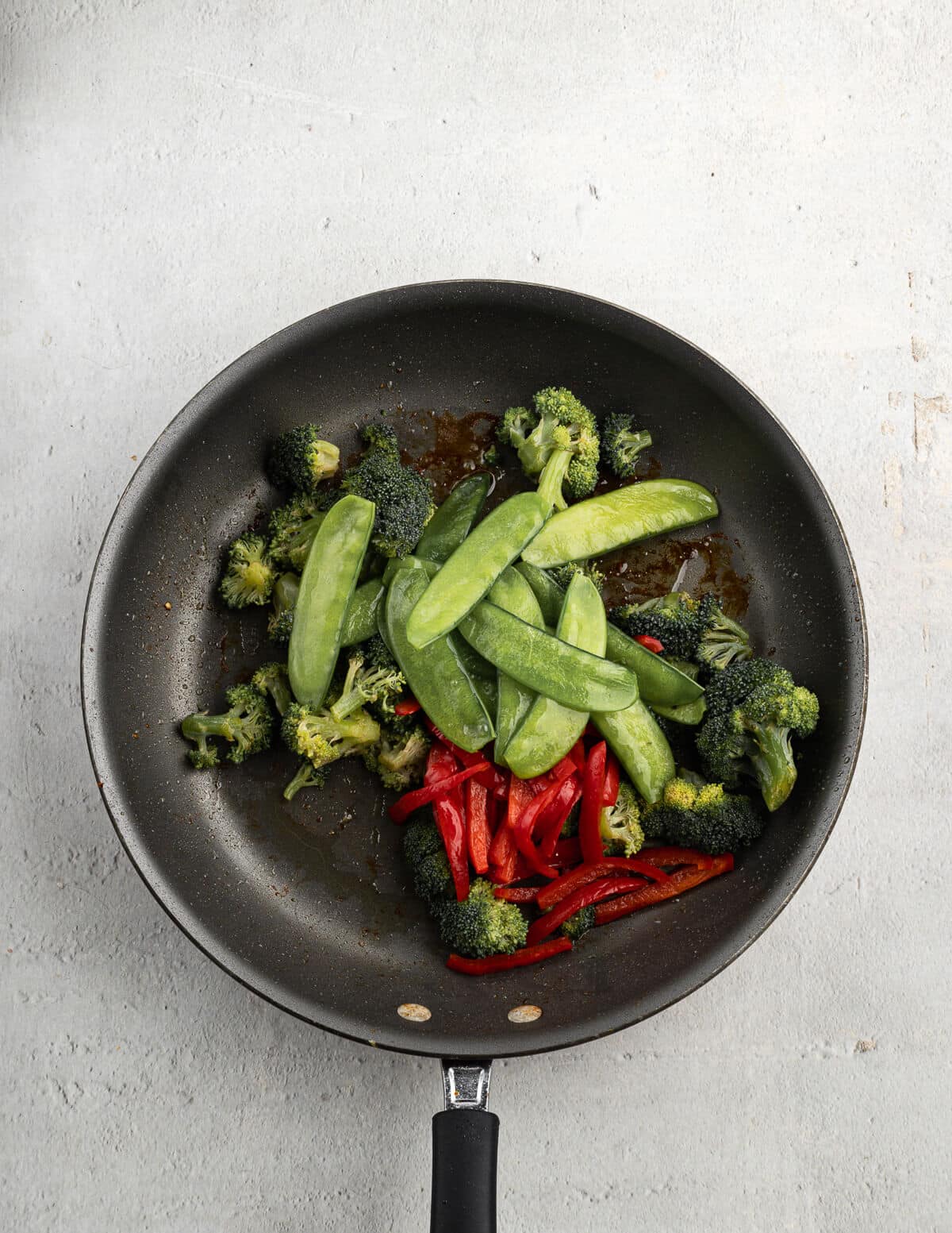 broccoli, snap peas, and bell peppers in a skillet with olive oil.