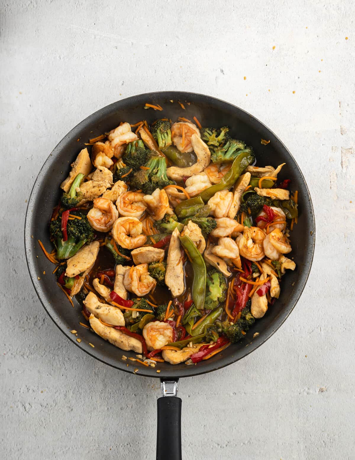 chicken and shrimp stir fry in a skillet.